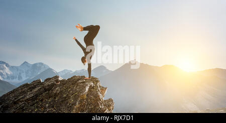 Erstaunlich yoga Mann sie einen Handstand auf Rock. Mixed Media Stockfoto