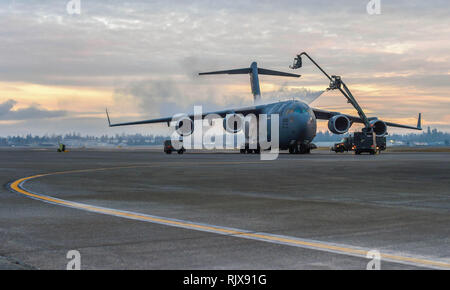 Die Flieger auf der 62 Aircraft Maintenance Squadron sprühen Sie eine C-17 Globemaster III zugeordnet mit flüssigem Entfrosterschalter bei Joint Base Lewis-McChord, Washington, Jan. 16, 2019. Eis und Schnee auf der Flight Control Oberflächen, wie der Schwanz und Flügel, können unbekannte aerodynamische Eigenschaften, kann das Flugzeug für den Start unsicher machen. (U.S. Air Force Foto von älteren Flieger Tryphäna Mayhugh) Stockfoto