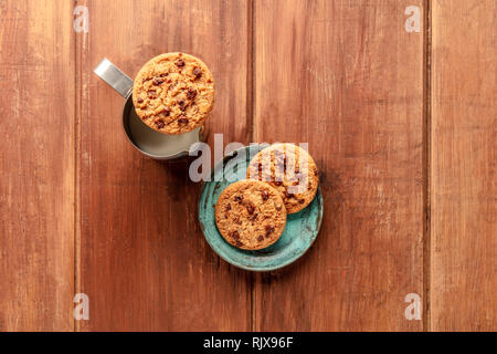 Chocolate Chip Cookies, Schuß von der Oberseite in einem dunklen Holzmöbeln im Landhausstil Hintergrund mit Milch und einen Platz für Text Stockfoto