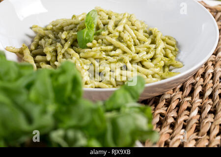 Nahaufnahme von einer Platte mit cremiger italienischer Trofie al pesto hinter Basilikum versteckt. Stockfoto