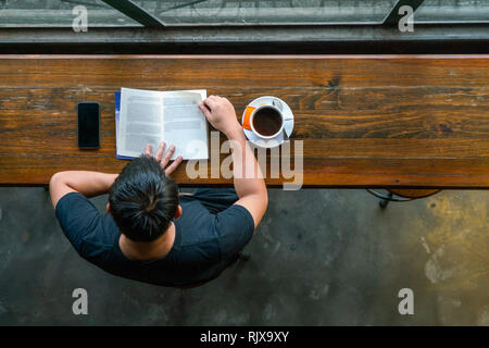 Blick von oben auf die jungen Mann lesen Buch Stockfoto