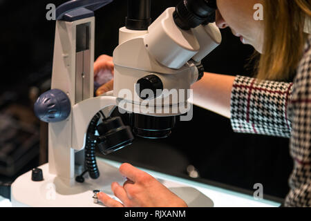 Junge Wissenschaftlerin durch ein Mikroskop im Labor auf der Suche Stockfoto