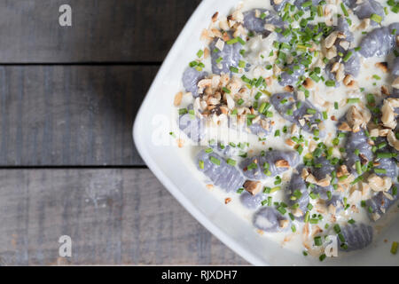 Ansicht von oben in der Nähe eines Gnocchi viola auf einem Holztisch. Violett italienische Gnocchi mit violetten Kartoffeln und fonduta von Gorgonzola, Mascarpone Stockfoto