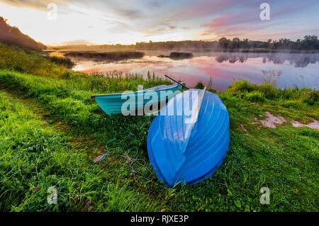 Einen schönen goldenen Sonnenuntergang am Fluss. Liebhaber können Fahrt in einem Boot auf einem See bei einem wunderschönen Sonnenaufgang. Cloud Spiegelungen im Wasser, bunte Himmel Stockfoto