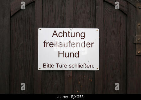 Text auf Deutsch: Achtung: Freilaufhund. Schließen Sie die Türen. Stockfoto