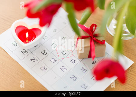 Geschenkbox, Kalenderblatt und Blumen auf dem Tisch Stockfoto