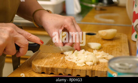 Ältere weibliche Hände Hacken von Zwiebeln auf Holzbrett in der Küche Stockfoto