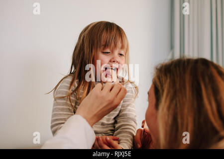 Ärztin für Halsschmerzen von Mädchen Patienten. Mädchen in Kehle Prüfung mit zungenspatel durch einen pädiatrischen Arzt. Stockfoto