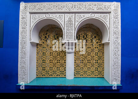 Die typischen, alten, reich verzierten, kunstvoll geschnitzten, Nieten, marokkanische Riad Fenster und Rahmen und altes Haus. Schöne Aussicht auf die blaue Wand in der Medina. Stockfoto
