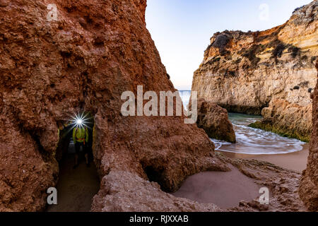 Mann, der Scheinwerfer unter Natural Arch von Cliff, Alvor, Algarve, Portugal, Europa Stockfoto