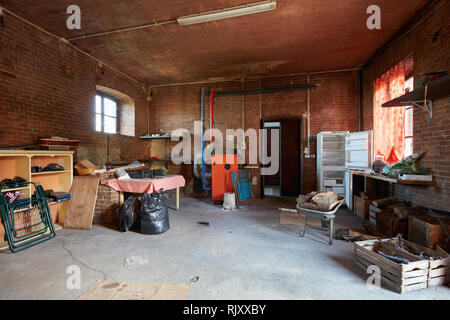 Unordentlicher Keller mit roten Ziegelsteinen Mauern im alten Landhaus Stockfoto