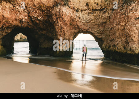 Mann erkunden Klippen und Felsformationen von Water's Edge, Alvor, Algarve, Portugal, Europa Stockfoto