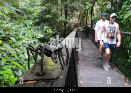 Touristen zu Fuß pas eine Ameise Skulptur entlang der Promenade im Barron Falls National Park, Kuranda, Far North Queensland, FNQ, QLD, Australien Stockfoto