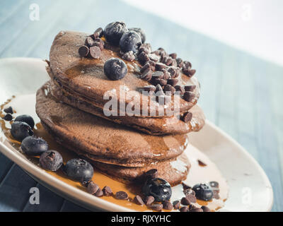 Kakao Pfannkuchen mit Schokolade Tropfen und Heidelbeeren, original amerikanisches Frühstück mit Ahornsirup Stockfoto