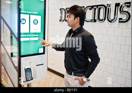 Inder Kunde bei Store Bestellungen aufgeben und durch selbst bezahlen, Kiosk für Fast food, Payment Terminal zahlen. Eine Wahl der Sprache auf dem Bildschirm machen. Stockfoto