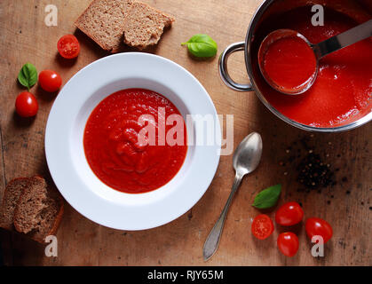 Hausgemachten Tomatensuppe in Weiß Platte auf dem Holztisch. Ansicht von oben Stockfoto