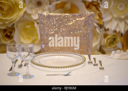 Sitzplatz in einer feierlichen Veranstaltung oder Fine Dining Restaurant mit transparenten Platten mit goldenen Details, Gläser und Besteck Stockfoto