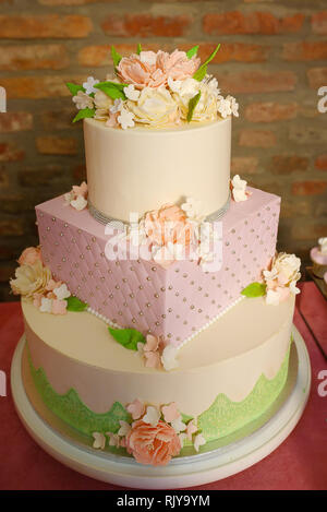 Andere Form drei tiered Kuchen für formelle Veranstaltungen, Hochzeiten oder Geburtstagsfeiern, mit samt Vereisung und Zucker Blumen und essbaren Schmuck verziert Stockfoto