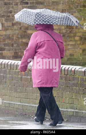 London, Großbritannien. 8 Feb, 2019. Eine Frau gesehen, die dem Schutz vor dem Regen unter einem Sonnenschirm während der starken Winde und der Regen in der Hauptstadt. Credit: Dinendra Haria/SOPA Images/ZUMA Draht/Alamy leben Nachrichten Stockfoto