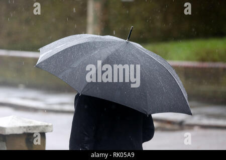 London, Großbritannien. 8 Feb, 2019. Ein Mann wird gesehen, Unterschlupf vor dem Regen unter einem Sonnenschirm während der starken Winde und der Regen in der Hauptstadt. Credit: Dinendra Haria/SOPA Images/ZUMA Draht/Alamy leben Nachrichten Stockfoto