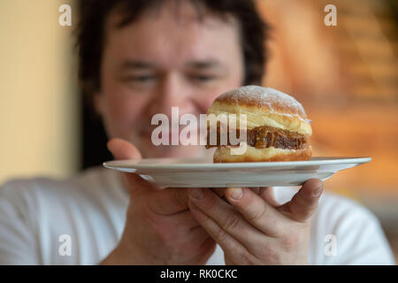 Miesbach, Deutschland. 07 Feb, 2019. Bäckermeister Florian Perkmann hält einen Donut mit Meat Loaf und süßen Senf gekrönt. Nach dem Leberkäs-Krapfen aus Oberbayern, die Goaßmaß-Krapfen kommt jetzt aus Niederbayern. Eine Goass Maßnahme ist ein gemischtes Getränk Bier, Cola und kirschlikör. (Dpa vom 09.02.2019) Credit: Lino Mirgeler/dpa/Alamy leben Nachrichten Stockfoto