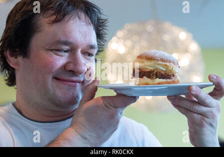Miesbach, Deutschland. 07 Feb, 2019. Bäckermeister Florian Perkmann hält einen Donut mit Meat Loaf und süßen Senf gekrönt. Nach dem Leberkäs-Krapfen aus Oberbayern, die Goaßmaß-Krapfen kommt jetzt aus Niederbayern. Eine Goass Maßnahme ist ein gemischtes Getränk Bier, Cola und kirschlikör. (Dpa vom 09.02.2019) Credit: Lino Mirgeler/dpa/Alamy leben Nachrichten Stockfoto