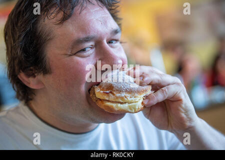 Miesbach, Deutschland. 07 Feb, 2019. Der Bäckermeister Florian Perkmann beißt in einen Donut, die mit Meat Loaf und süßen Senf in seiner Hand gekrönt wurde. Nach dem Leberkäs-Krapfen aus Oberbayern, die Goaßmaß-Krapfen kommt jetzt aus Niederbayern. Eine Goass Maßnahme ist ein gemischtes Getränk Bier, Cola und kirschlikör. (Dpa vom 09.02.2019) Credit: Lino Mirgeler/dpa/Alamy leben Nachrichten Stockfoto