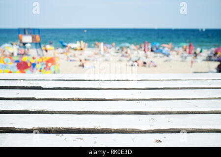 Holz Tisch mit unscharfen Menschen am Strand als Hintergrund Stockfoto