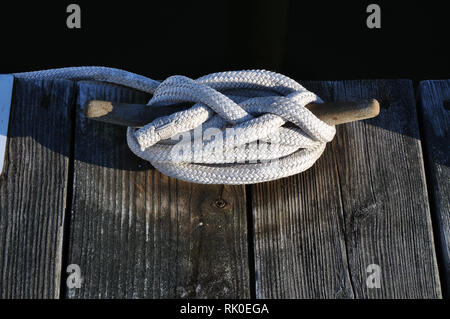 Ein Metall Keil, ein Dock mit einem weißen Seil gebunden. Stockfoto