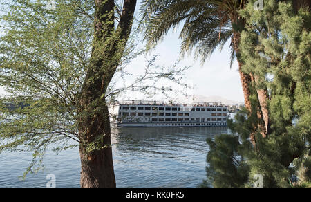 Große luxuriöse traditionelle ägyptische River Cruise Yacht segeln auf dem Nil durch Bäume gerahmt Stockfoto