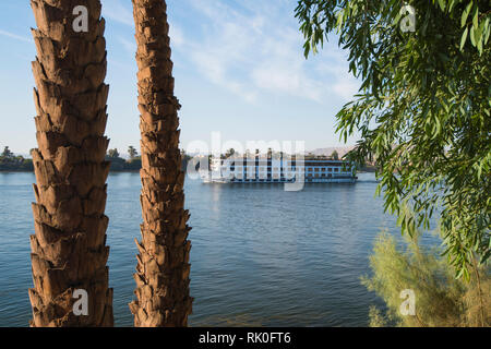 Große luxuriöse traditionelle ägyptische River Cruise Yacht segeln auf dem Nil durch Bäume gerahmt Stockfoto