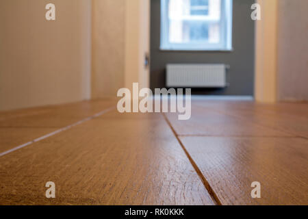 Geräumige Zimmer, Holzboden Hellbraun polierte Oberfläche Hintergrund in der neuen Wohnung Interieur, beige Wände, verschwommenes Glas Fenster oder eine Tür öffnen Stockfoto