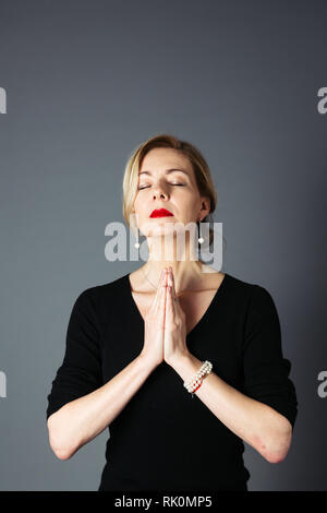 Porträt der schönen Frau in einem schwarzen Kleid vor grauem Hintergrund Stockfoto