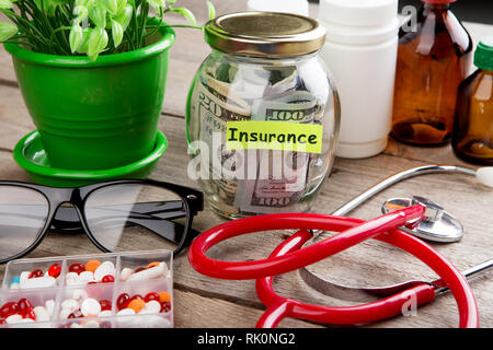 Geld sparen für Krankenversicherung - Geld Glas, Stethoskop, Pillen und Flaschen Stockfoto