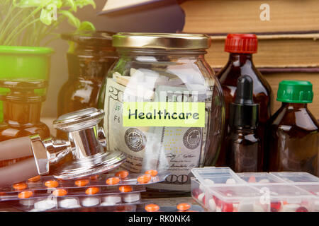Geld sparen für Krankenversicherung - Geld Glas, Stethoskop, Pillen und Flaschen Stockfoto