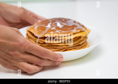 Pfannkuchen mit Kondensmilch auf einem weißen Hintergrund. Einen Stapel Pfannkuchen mit süßen Soße. Nähe zu sehen. Stockfoto