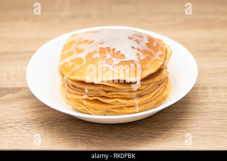 Pfannkuchen mit Kondensmilch auf einem weißen Hintergrund. Einen Stapel Pfannkuchen mit süßen Soße. Nähe zu sehen. Stockfoto