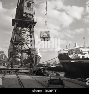 1950 s, East Ferry, Nr. 3, Isle of Dogs, London Docks, einen Kran Verlagerung von Güterverkehr vom Schiff, Kisten der Agar. Zu dieser Zeit ist die Docklands von London arbeiteten in der Industrie, sondern aus den 1960er-Jahren rückläufig, wie die größeren Schiffe, die nicht in der engen Wasserstraßen untergebracht werden könnte. Stockfoto