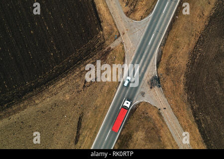 Autos und Lastwagen auf der geraden Straße durch die ebene Landschaft Landschaft, Luftaufnahme von Drone pov Stockfoto