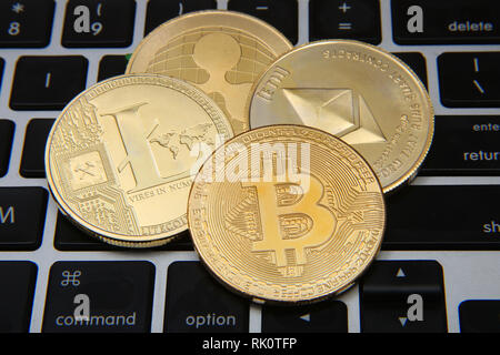 Litecoin, Welligkeit, des Astraleums & Bitcoin Goldmünzen, die cryptocurrenies gegen einen Laptop Tastatur Hintergrund. Stockfoto