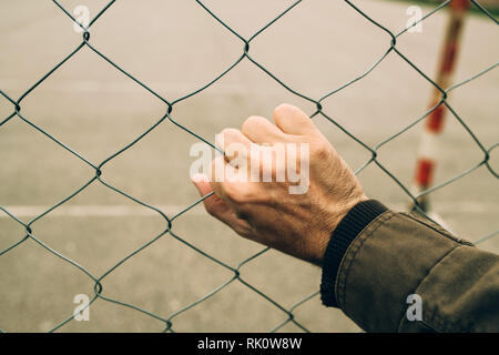 Männliche hand auf chainlink Fence, illegale Einwanderung Konzept