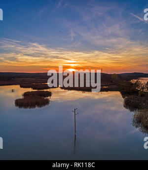 Schöne Luftaufnahme am See mit bunten Bäumen im Herbst. Malerische Küste bei Sonnenuntergang Stockfoto