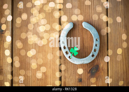 Hufeisen mit Kleeblatt auf hölzernen Hintergrund Stockfoto