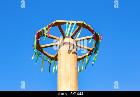 Faschings Feier in Russland. Holz- rad mit bunten Bändern auf blauen Himmel Hintergrund Stockfoto