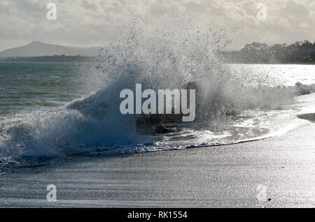 Wellen auf die Felsen auf killiney Beach, Dublin, Irland, von der Sonne beschienen, von mächtigen onshore Wind angetrieben. Stockfoto