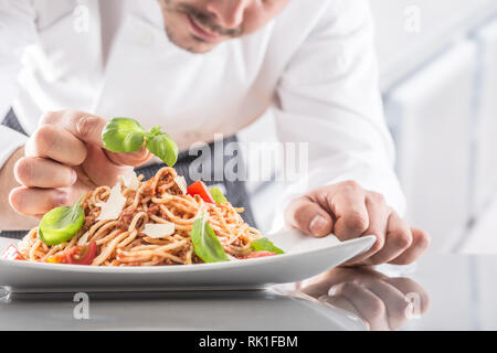 Küchenchef im Restaurant Küche bereitet und schmückt Mahlzeit mit Händen. Kochen Vorbereitung Spaghetti Bolognese. Stockfoto