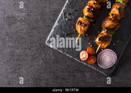 Hühnchen Shish Kebab mit Gemüse auf schwarzem Stein. Ansicht von oben. Copyspace Stockfoto