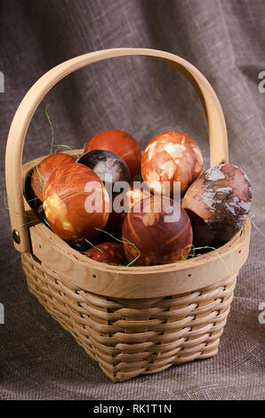 Ostern Eier. Braun bemalte Eier im Korb auf braunem Hintergrund. Stockfoto