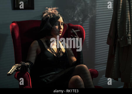 Frau mit einem Gewehr, das Rauchen einer Zigarette, Film Noir Stil Stockfoto