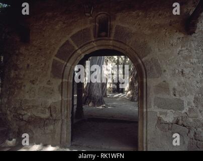 PUERTA DE MEDIO PUNTO EN EL MURO DE CIERRE - ENTRADA AL CONJUNTO MONACAL - IGLESIA AL FONDO. Lage: Monasterio. CACERES. Spanien. Stockfoto